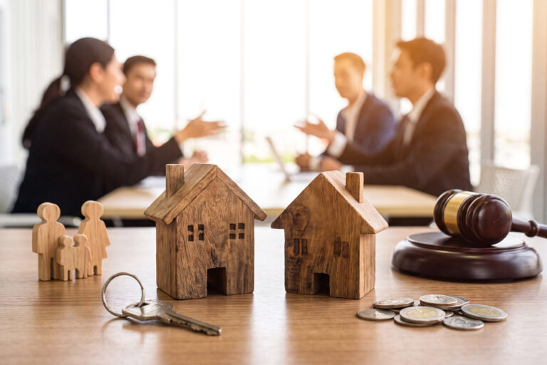 A gavel house models and a key on a table symbolizing a real estate transaction during a meeting with legal advisors.